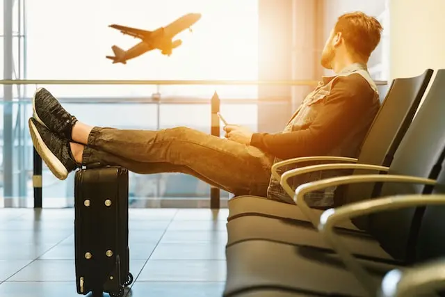 Photo d'un homme attendant à l'aéroport le départ de son avion pour aller fêter un EVG/EVJF à l'étranger
