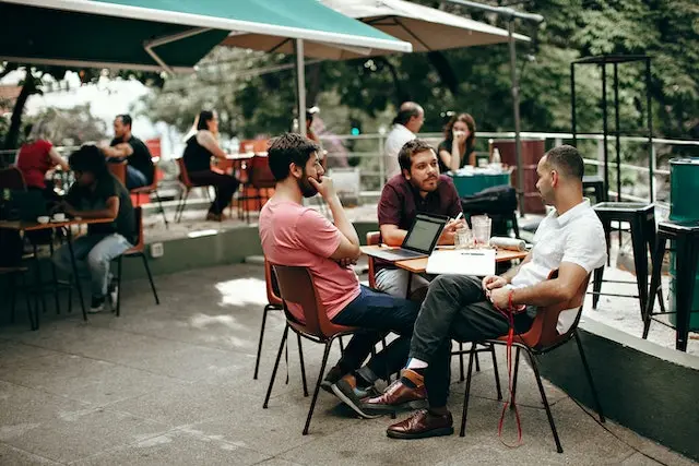 Hommes assis à une terrasse de café qui réfléchissent pour organiser un EVG réussi en 2023